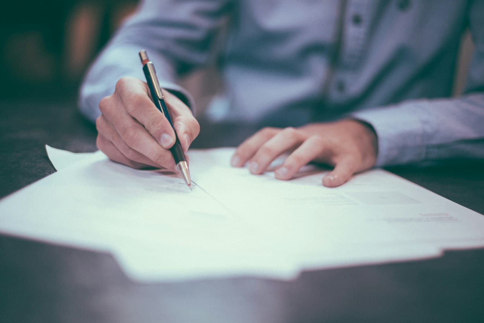 A person carefully reviewing and signing a document